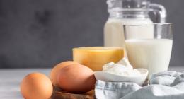 Dairy products arranged on a table: milk in a jug, cheese and eggs