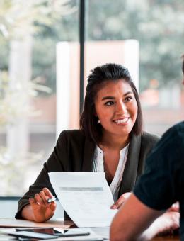 une femme souriante face à un homme qui tient un document dans les mains