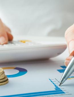 une personne écrivant sur une charte et utilisant une calculatrice