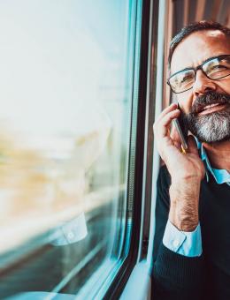 Homme au téléphone assis à coté d'une fenêtre dans un train