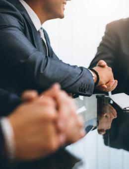 deux hommes qui se serrent la main et un troisième homme dont seulement les mains sont visibles