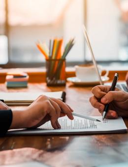 Hands visibe pointing to and signing a contract