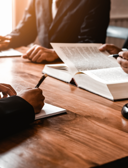 People sitting around a table writing in books and on papers, only their hands are visible