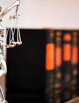 Statue holding a scale with legal books in the background