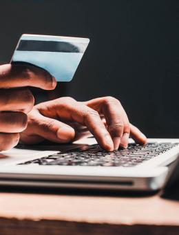 Person holding a bank card in front of a laptop