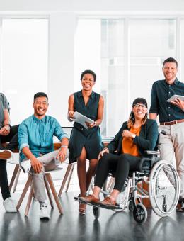 A diverse group of people smiling while facing the camera in front of a table.