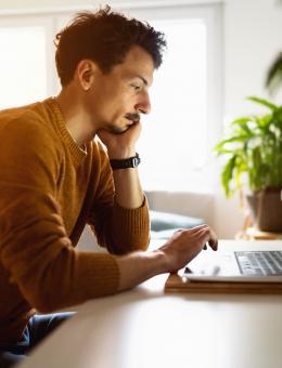 Man looking at computer screen with greenery in the background