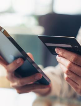 Woman paying online using mobile phone and bank card, only her upper body are visible